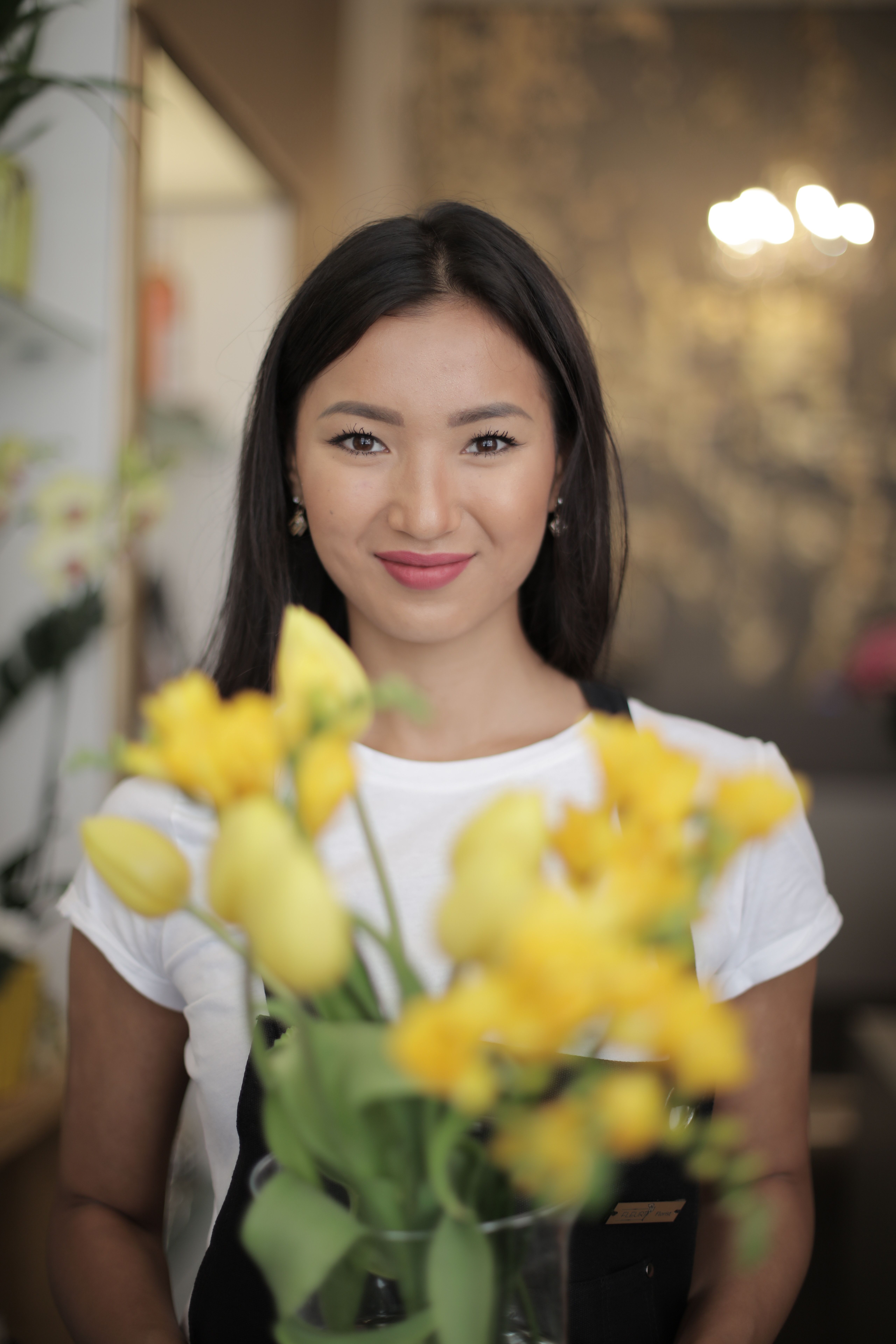 Woman in White Crew neck T-shirt Wearing Black Apron Holding Flowers ...