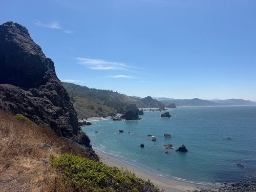 Free Beautiful view of the Oregon coastline with rocky cliffs and clear blue ocean under a sunny sky. Stock Photo