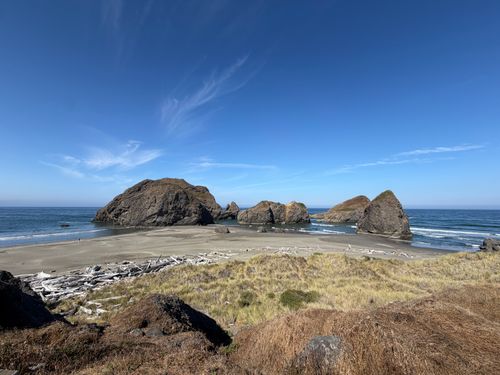 Free Serene view of rocky formations on a sandy beach along the Oregon coast under a clear blue sky. Stock Photo