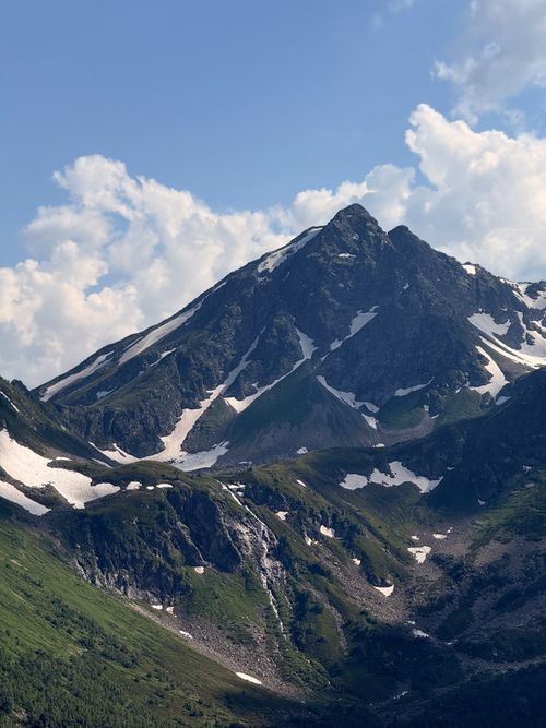 Free Snow-capped Mount Elbrus under a clear blue sky with lush green valleys in the Caucasus region, Russia. Stock Photo