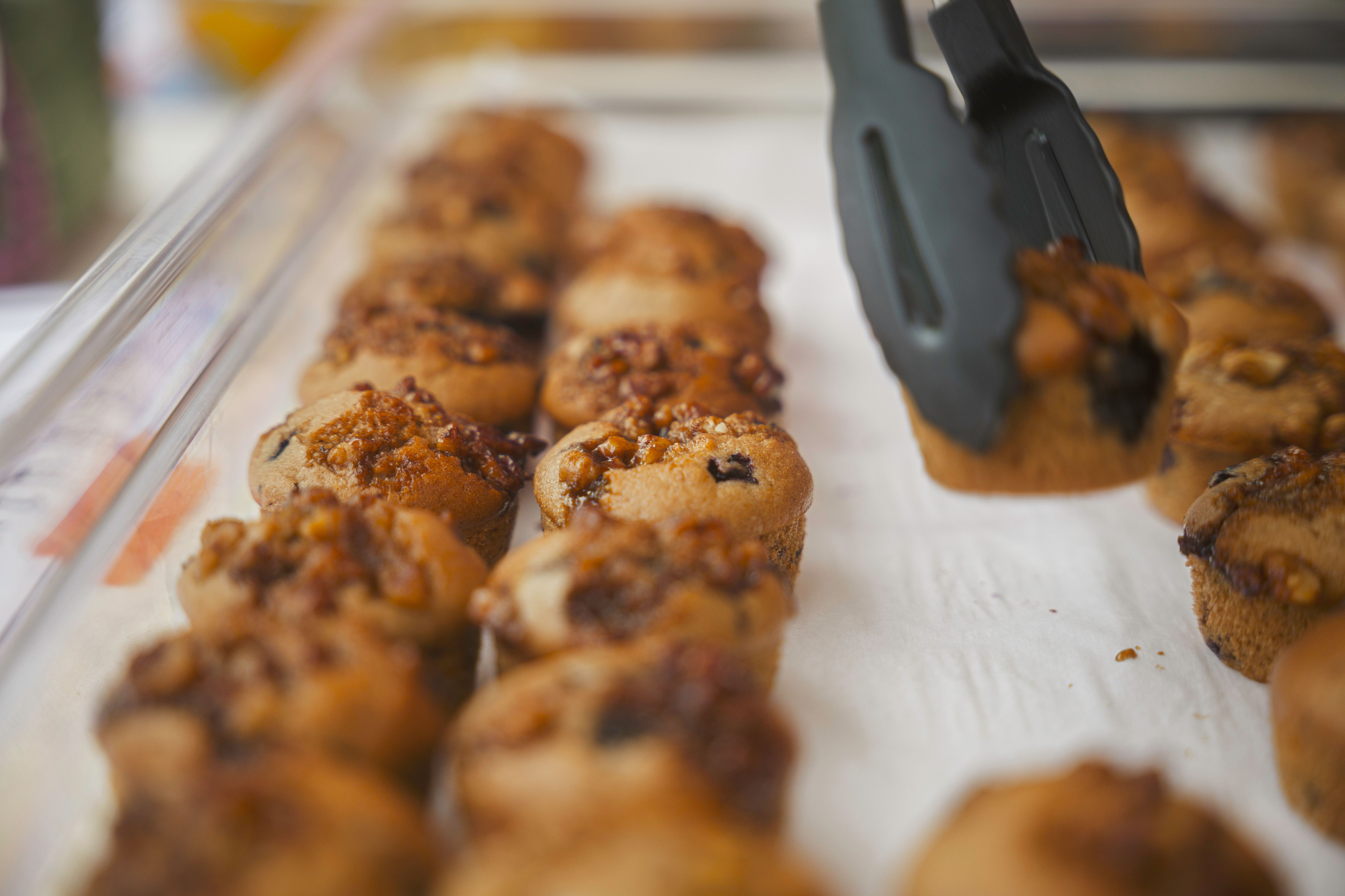 Close-up of freshly baked muffins topped with nuts and berries, lined on a tray.