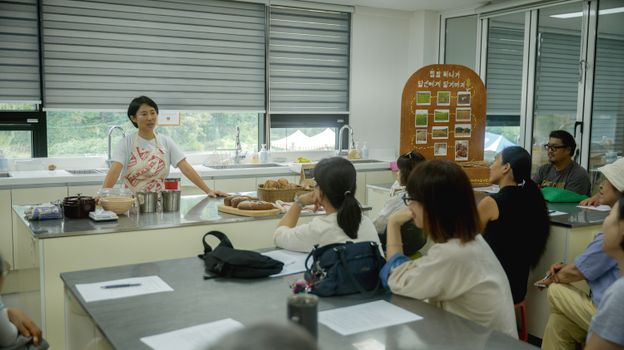 Cooking instructor teaching diverse adult class in kitchen setting.