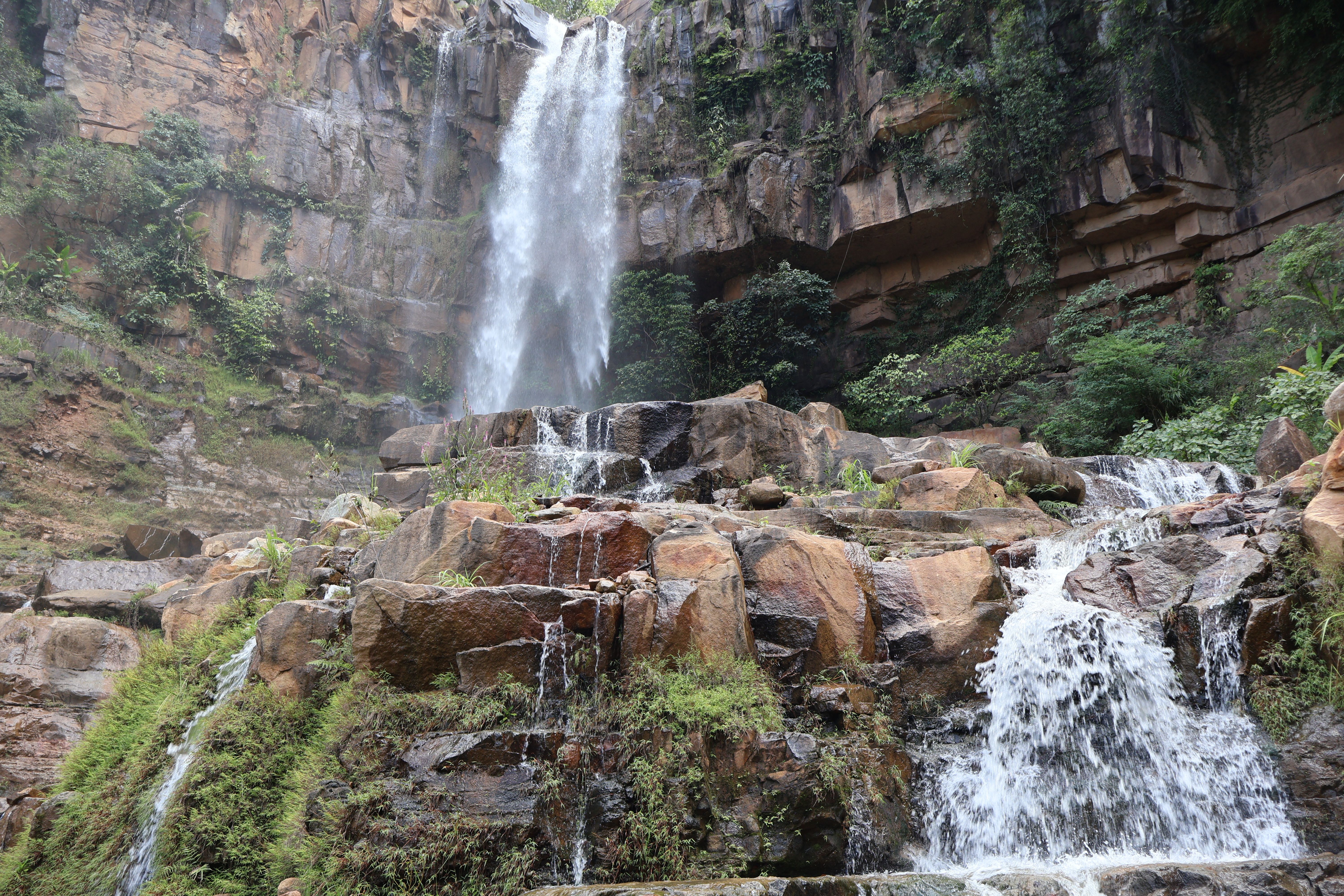 Stunning waterfall cascading down rocky cliffs surrounded by lush greenery.