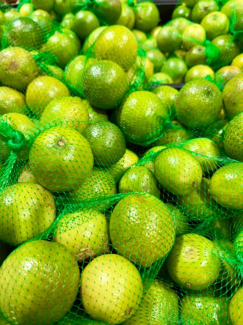 Free Vibrant green limes encapsulated in mesh bags, captured at a Melbourne market. Stock Photo
