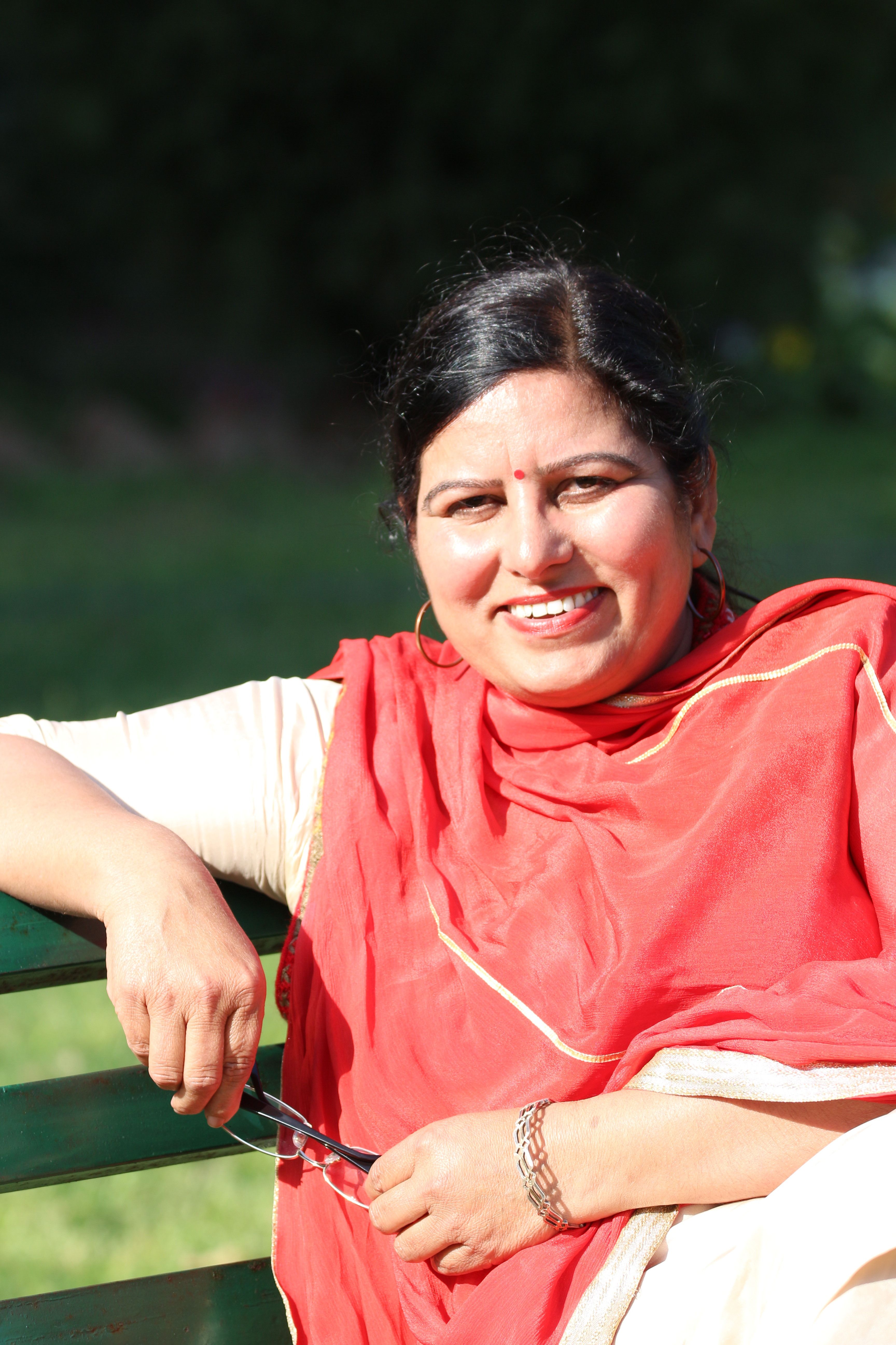 Portrait of a cheerful woman in traditional attire relaxing outside on a sunny day.