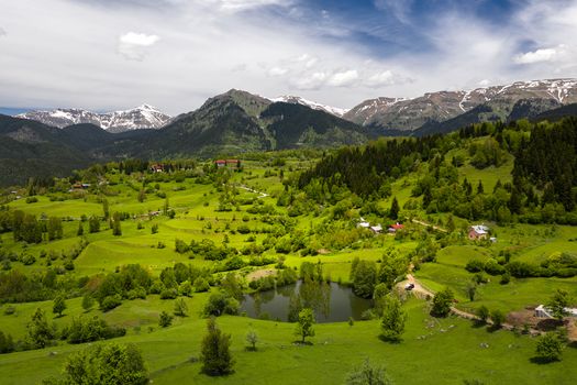 Lush green valley with distant mountains under a bright sky in the Georgian countryside.