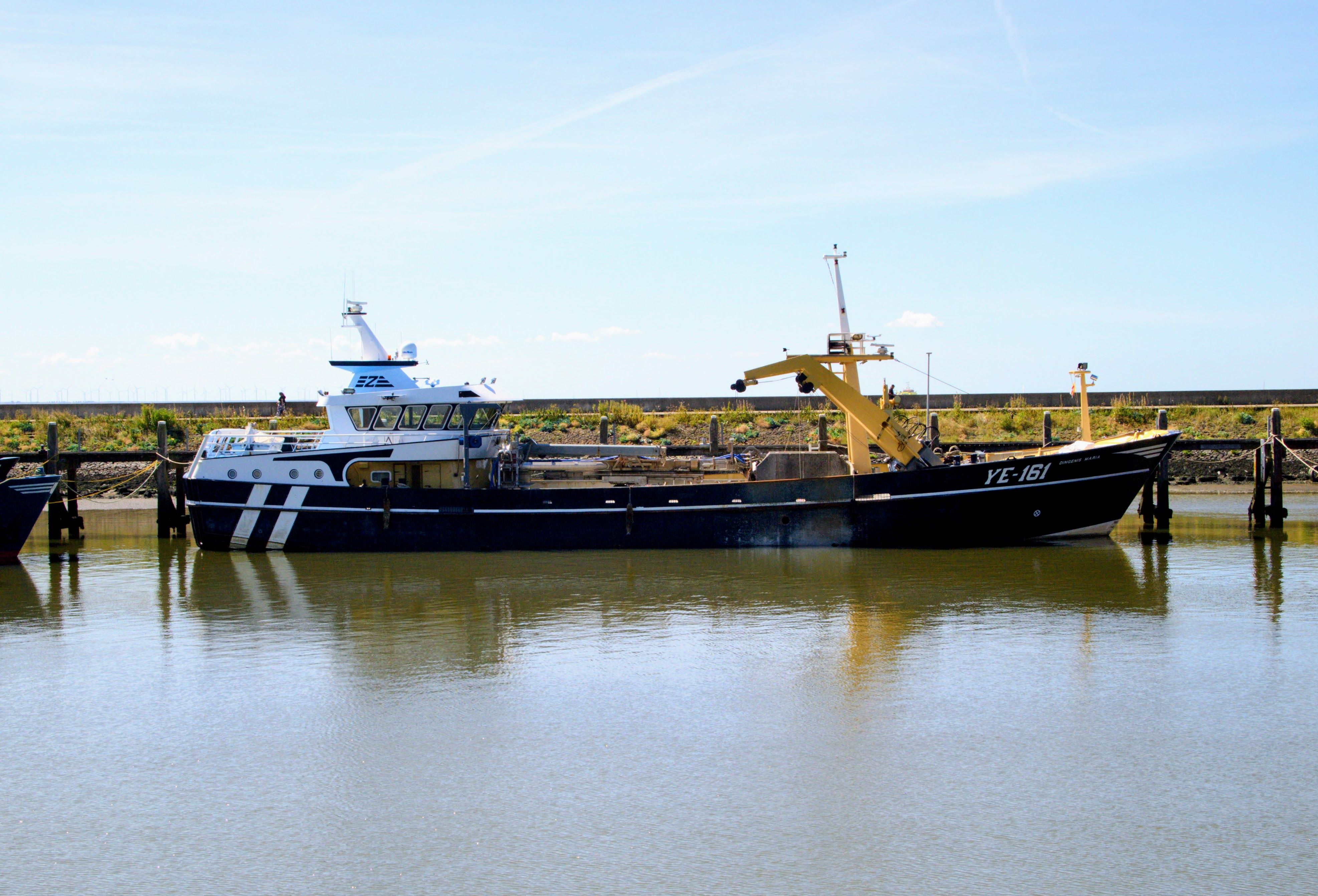 A fishing vessel YC-161 moored in Harlingen harbor, under a clear blue sky.