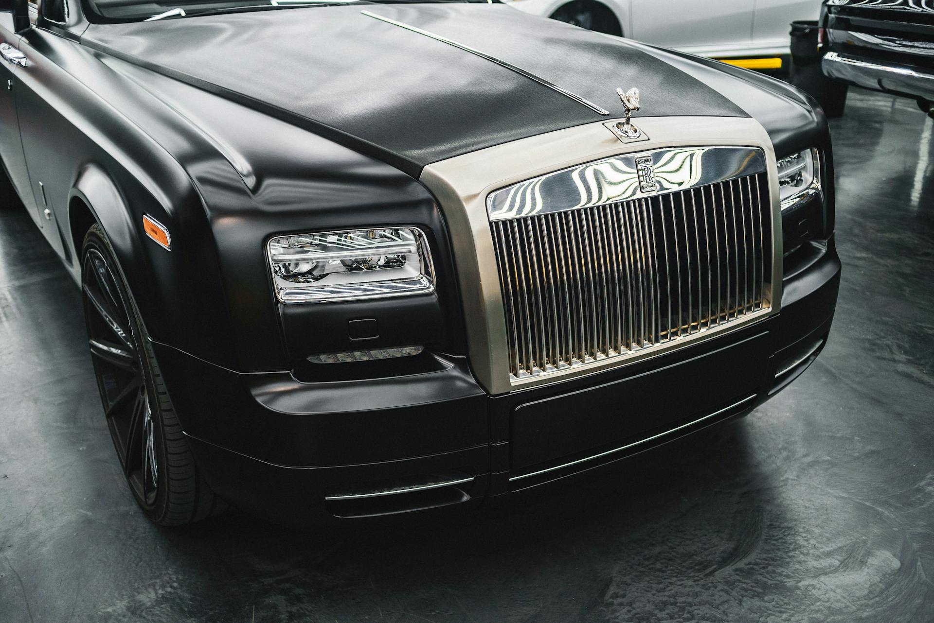 Close-up of a luxurious black car showcasing the iconic grille and hood design, highlighting elegance and sophistication.