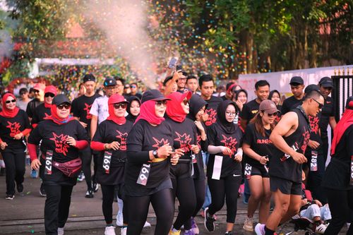 Free A lively fun run event with diverse adult participants wearing black shirts, set in an outdoor festive atmosphere. Stock Photo