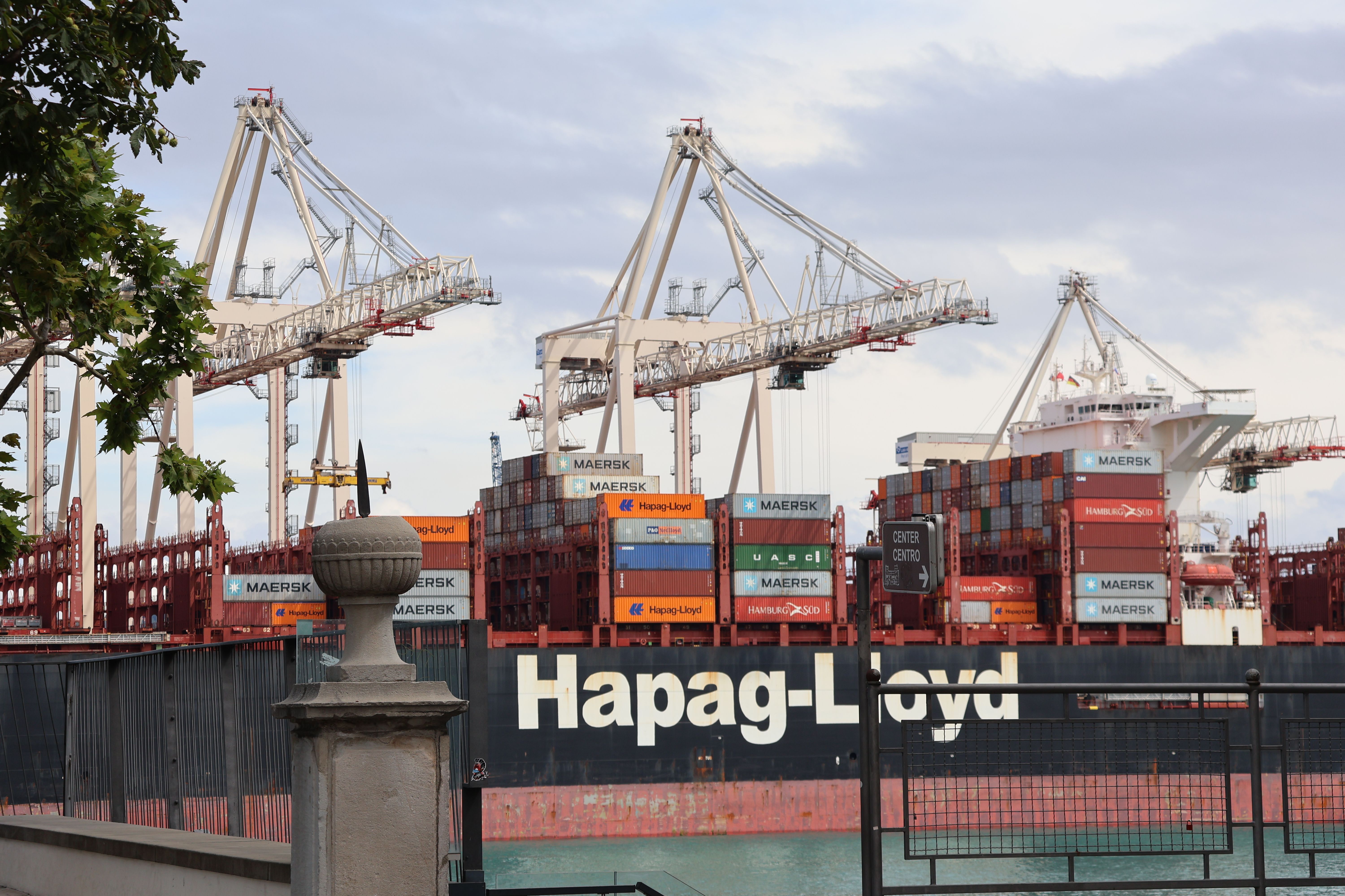 A container ship unloading cargo at a busy industrial port with large cranes and stacked containers.