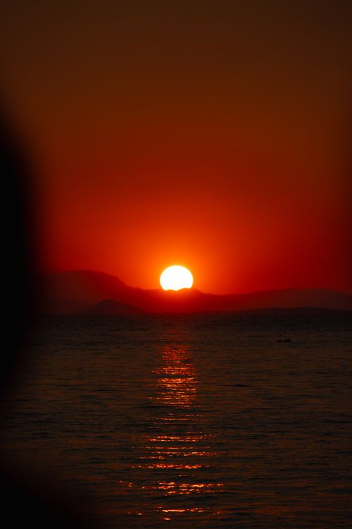 Free Captivating sunset over the sea in Greece with vibrant orange hues reflecting on the water. Stock Photo