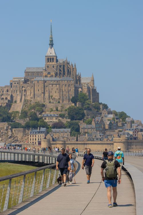 Free Visitors walk towards the majestic Mont Saint-Michel in Normandy, France, on a sunny day. Stock Photo