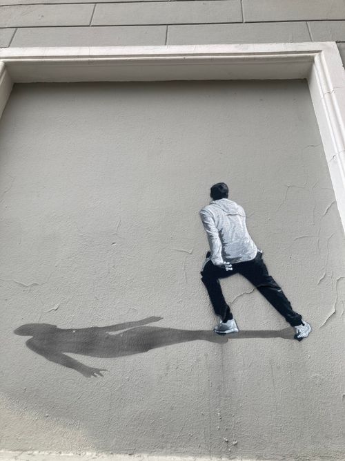 Free Unique street art mural depicting a person casting a shadow on a building wall. Stock Photo