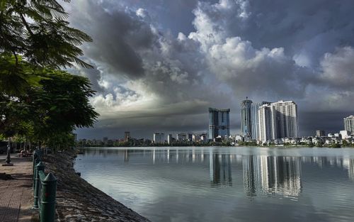Free Breathtaking view of Vân Đồn's skyline reflecting in the serene lake under dramatic clouds. Stock Photo