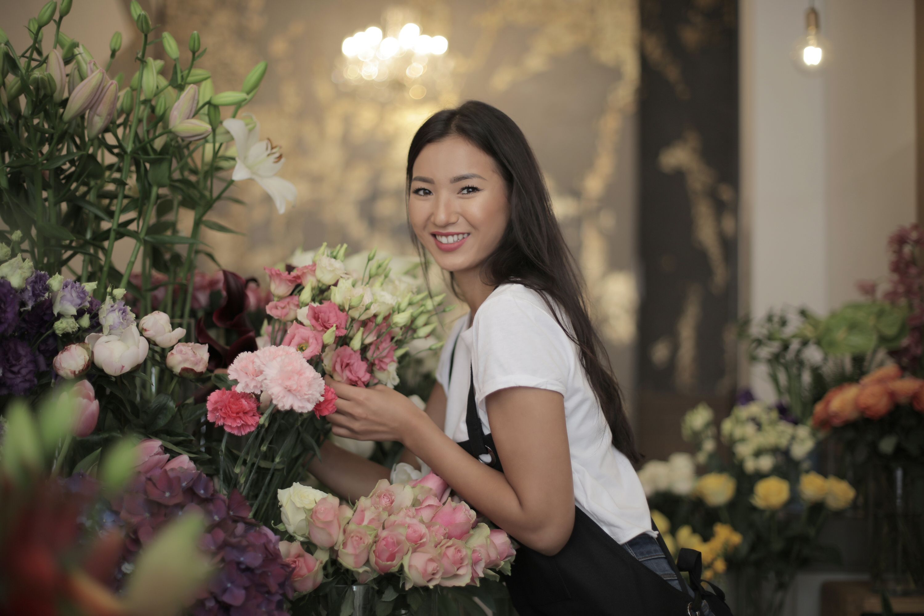 花店里，一位面带微笑的店员正摆放着各式各样的鲜花