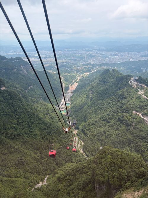 Free Aerial view of cable cars traveling over the vibrant green mountains in China, showcasing breathtaking natural beauty. Stock Photo