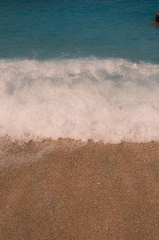 Gentle ocean wave meets a sandy shoreline in Lefkada, Greece. Perfect vacation scene.