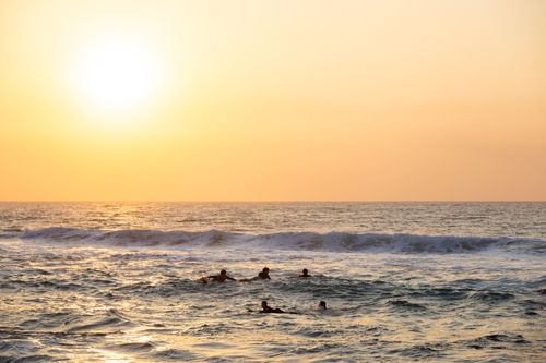Free People enjoy swimming in the ocean at sunset with waves and a golden sky. Stock Photo