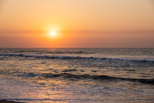 Free A breathtaking view of a golden sunset over gentle ocean waves. Stock Photo