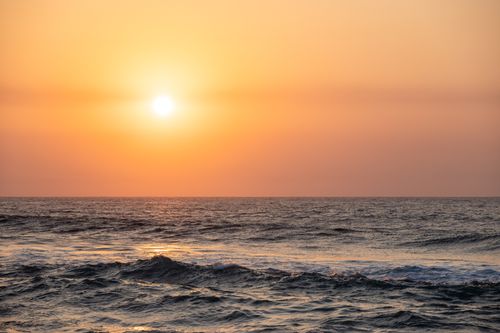 Free A mesmerizing ocean sunrise casting golden hues over the waves, creating a tranquil scene. Stock Photo