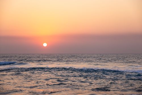 Free Beautiful ocean sunset with vibrant sky and tranquil waves rolling gently. Stock Photo