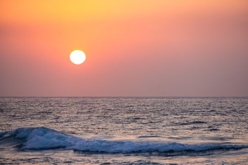 Free A breathtaking sunset over the ocean with peaceful waves and vibrant orange hues. Stock Photo