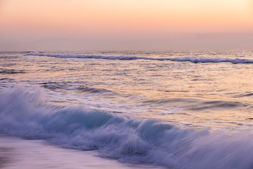 Free Tranquil ocean waves captured at sunset, creating a peaceful seascape with soft pastel hues. Stock Photo