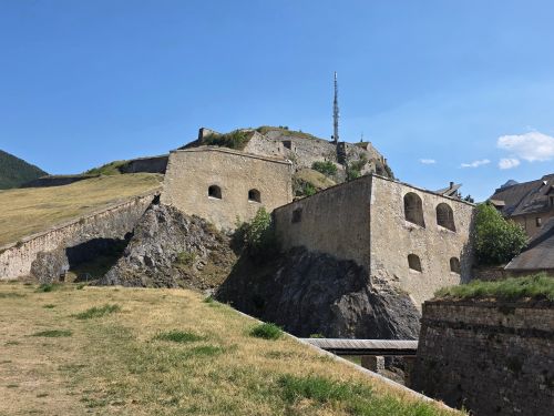 Free A stone fortress on a hill under a clear blue sky with surrounding greenery. Stock Photo