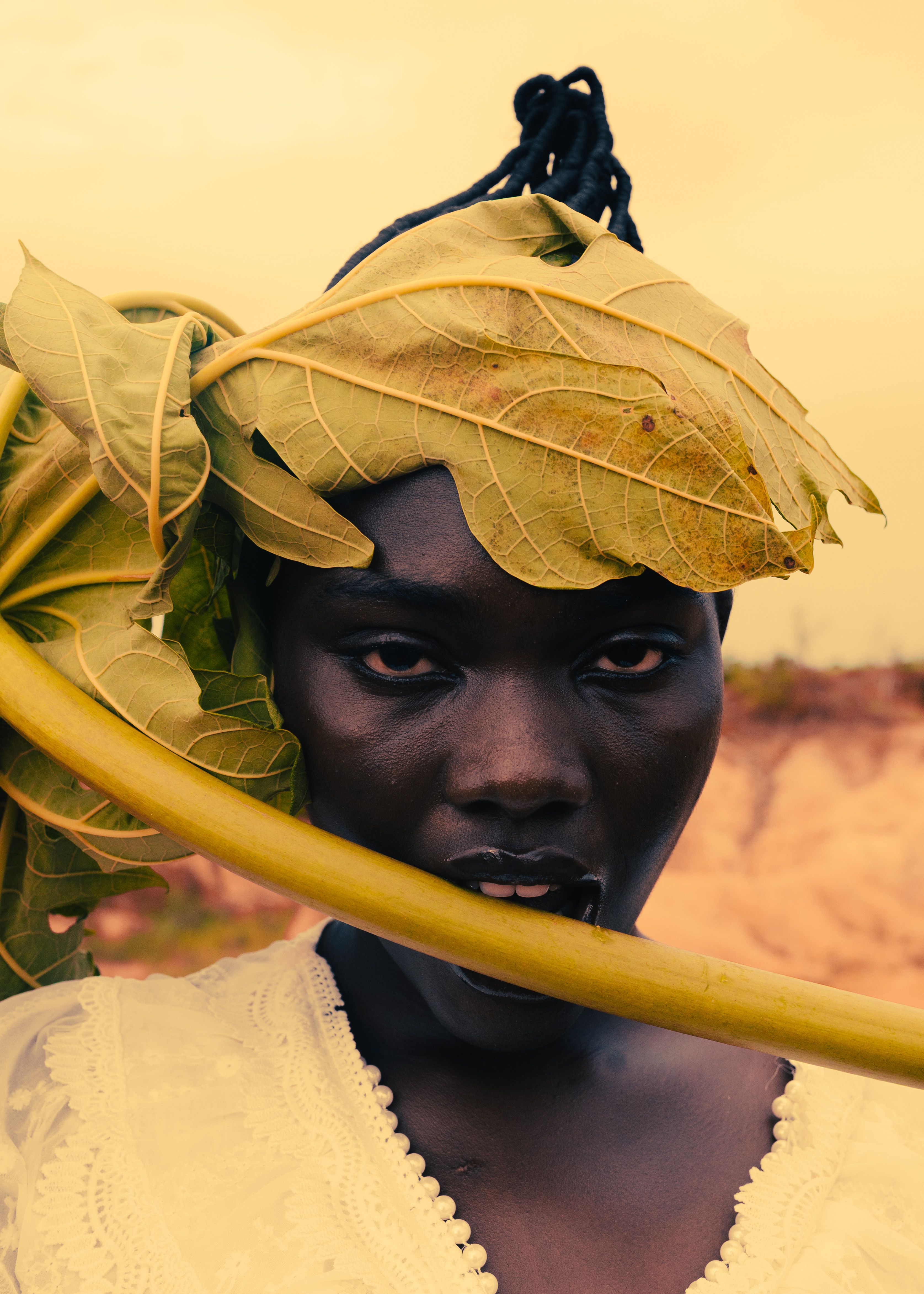 A striking portrait of a person with a large leaf headdress, showcasing natural beauty and bold style.