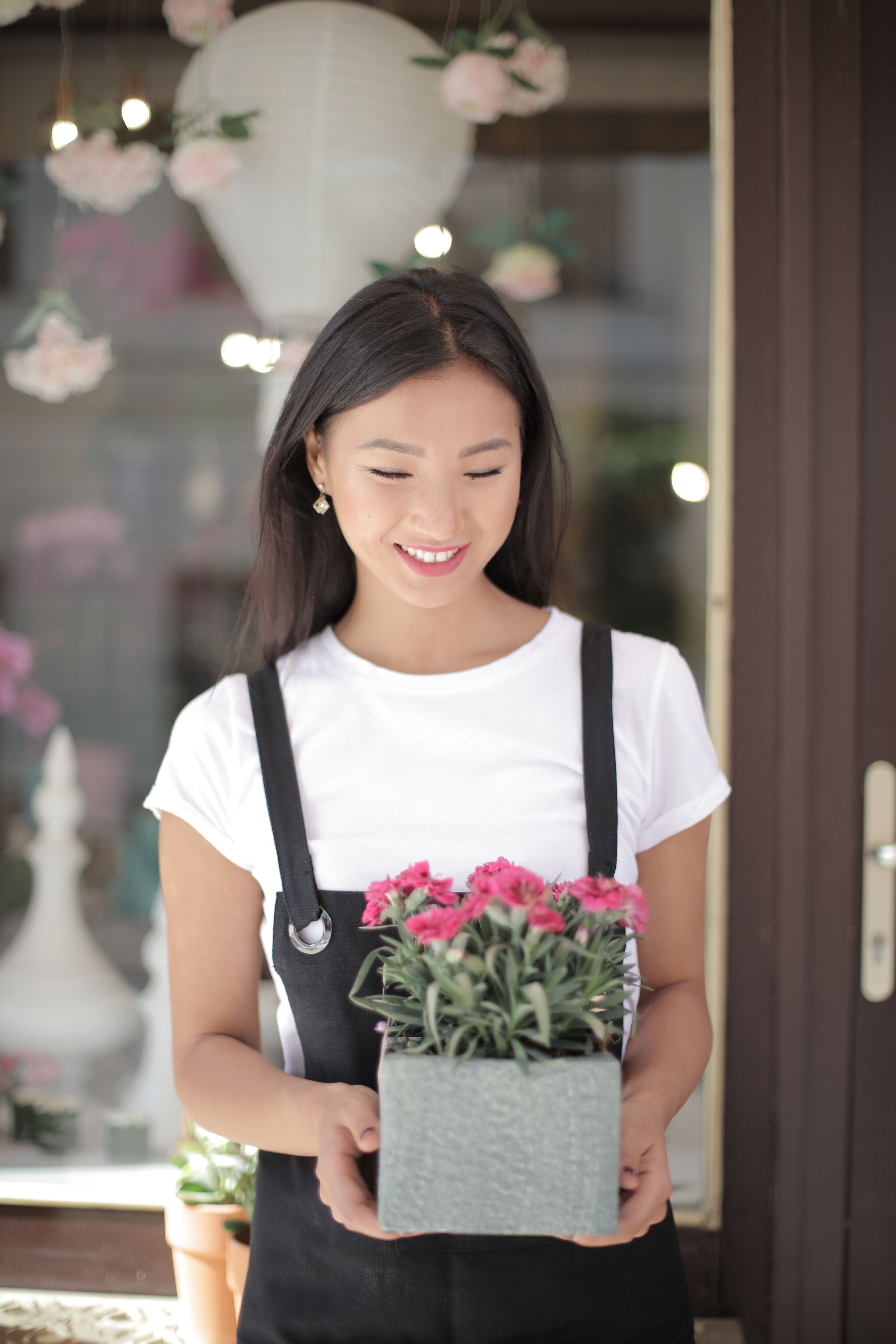Woman in White Crew neck T-shirt Wearing Black Apron Holding Flowers ...