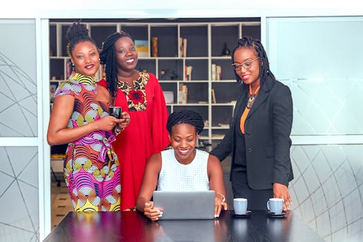 Group of African women professionals collaborating around a laptop indoors.