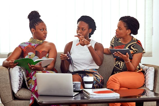 Three African American women engaged in a collaborative business meeting indoors.