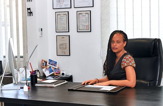 Businesswoman sitting at a desk in a contemporary office space with certificates on the wall.
