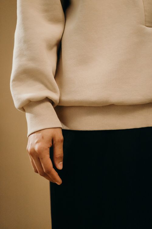 Free A detailed view of a person wearing a beige sweatshirt and black pants in a relaxed setting. Stock Photo