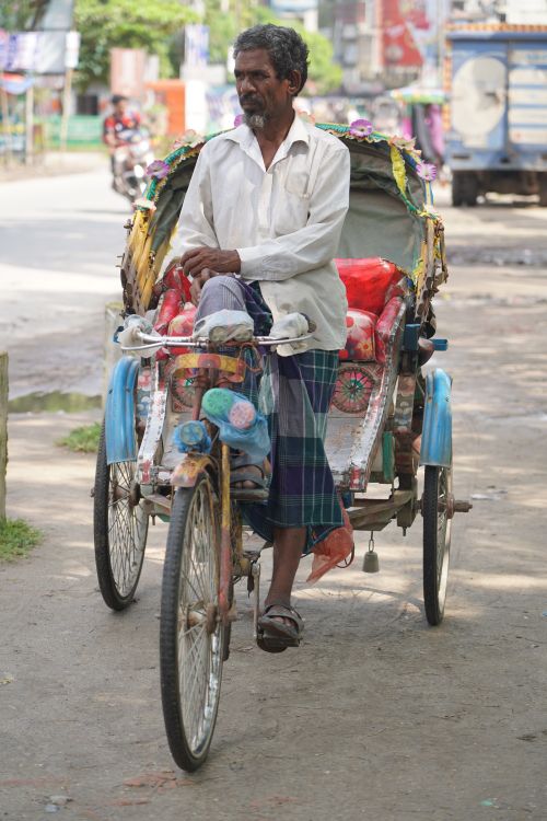 Free A local rickshaw puller navigates a village street in Bangladesh, showcasing traditional local transport. Stock Photo
