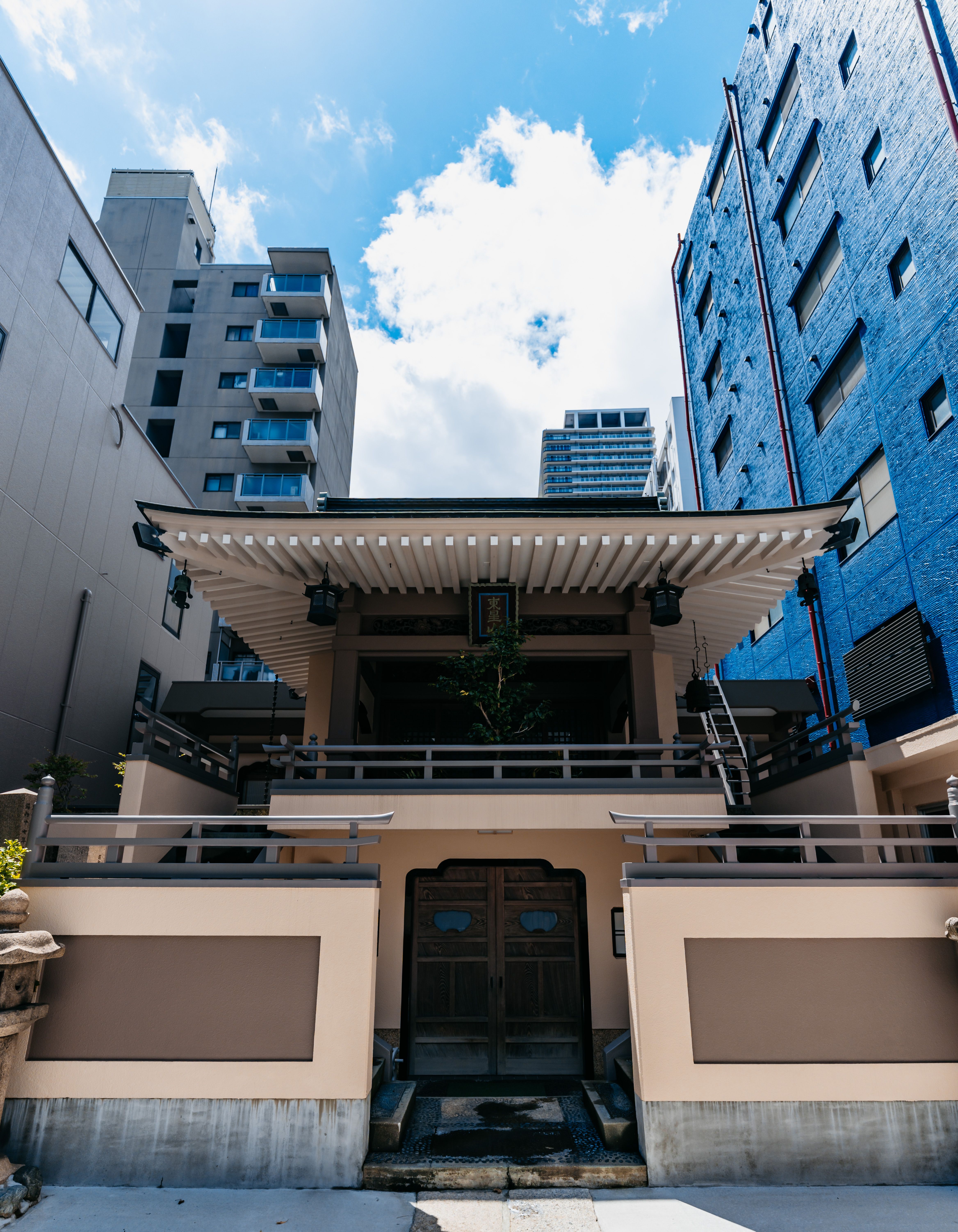 A traditional temple juxtaposed with modern architecture under a bright blue sky.