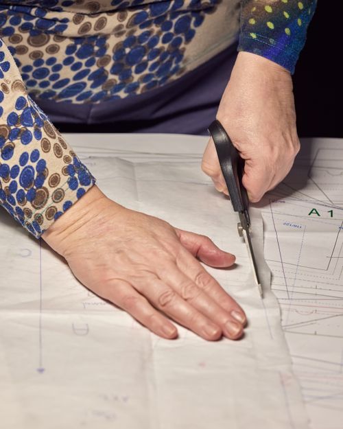 Free Detailed image of hands precisely cutting a sewing pattern, perfect for DIY fashion projects. Stock Photo