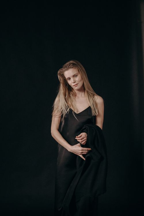 Free Graceful portrait of a woman in a black dress with a serene expression in a studio setting. Stock Photo
