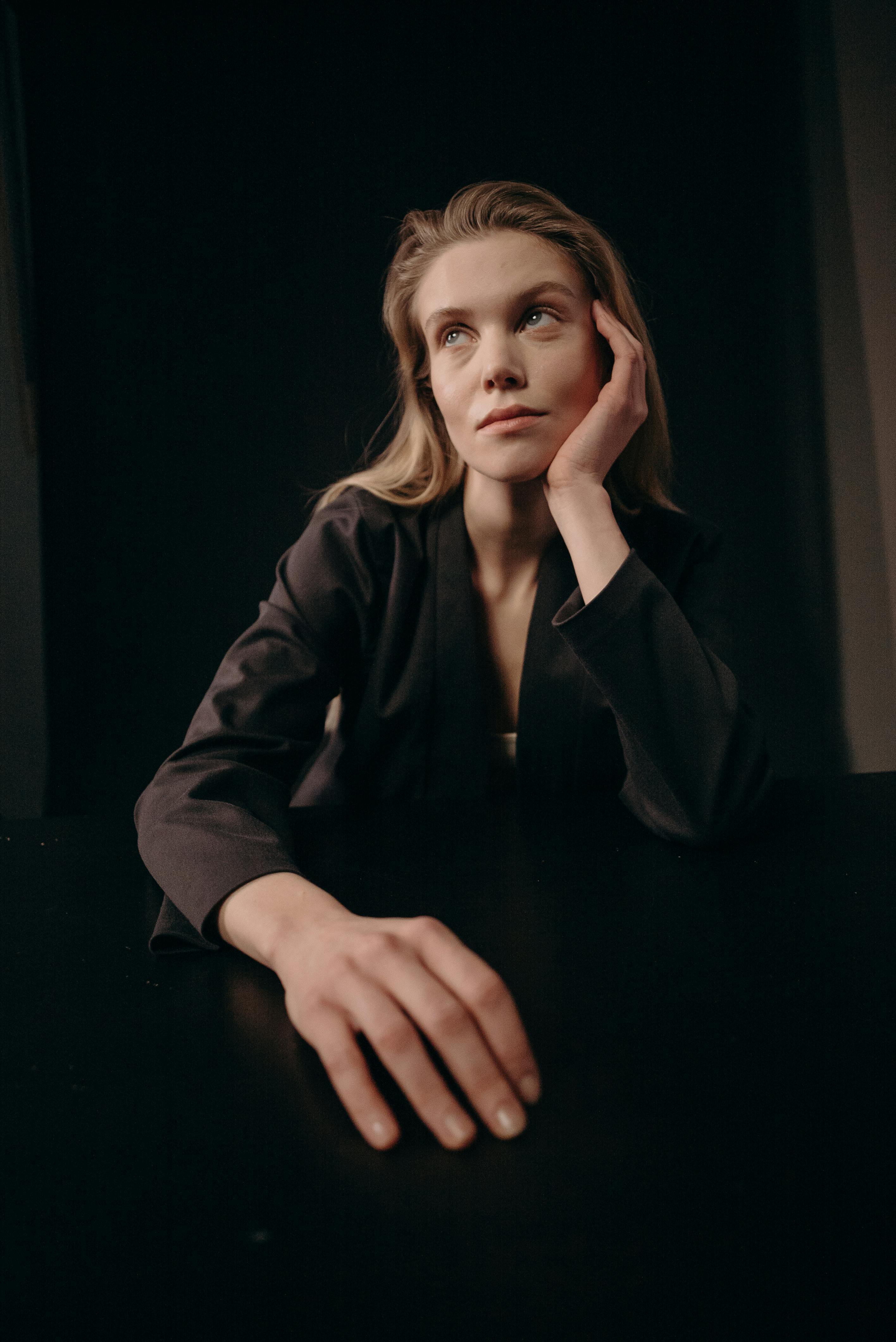 在黑暗背景下，一位沉思的女人凝视着远方的肖像