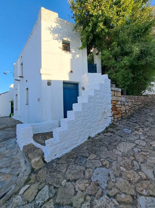 Free Mediterranean white house with blue door and stone steps under clear blue sky. Stock Photo