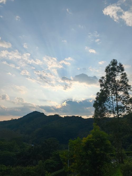 Free Beautiful mountain landscape with sun rays piercing through clouds at sunset. Stock Photo