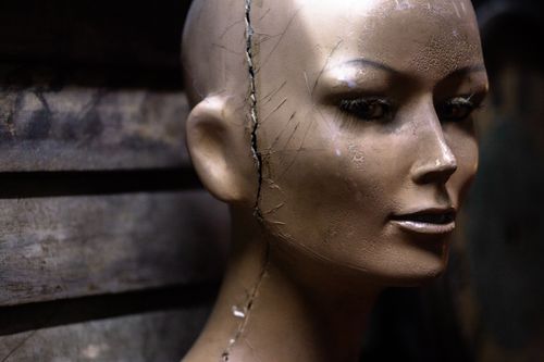 Free Close-up of a cracked mannequin head with dramatic texture in a rustic environment. Stock Photo