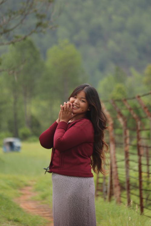 Free Smiling woman in a red sweater enjoying a serene, natural environment. Stock Photo