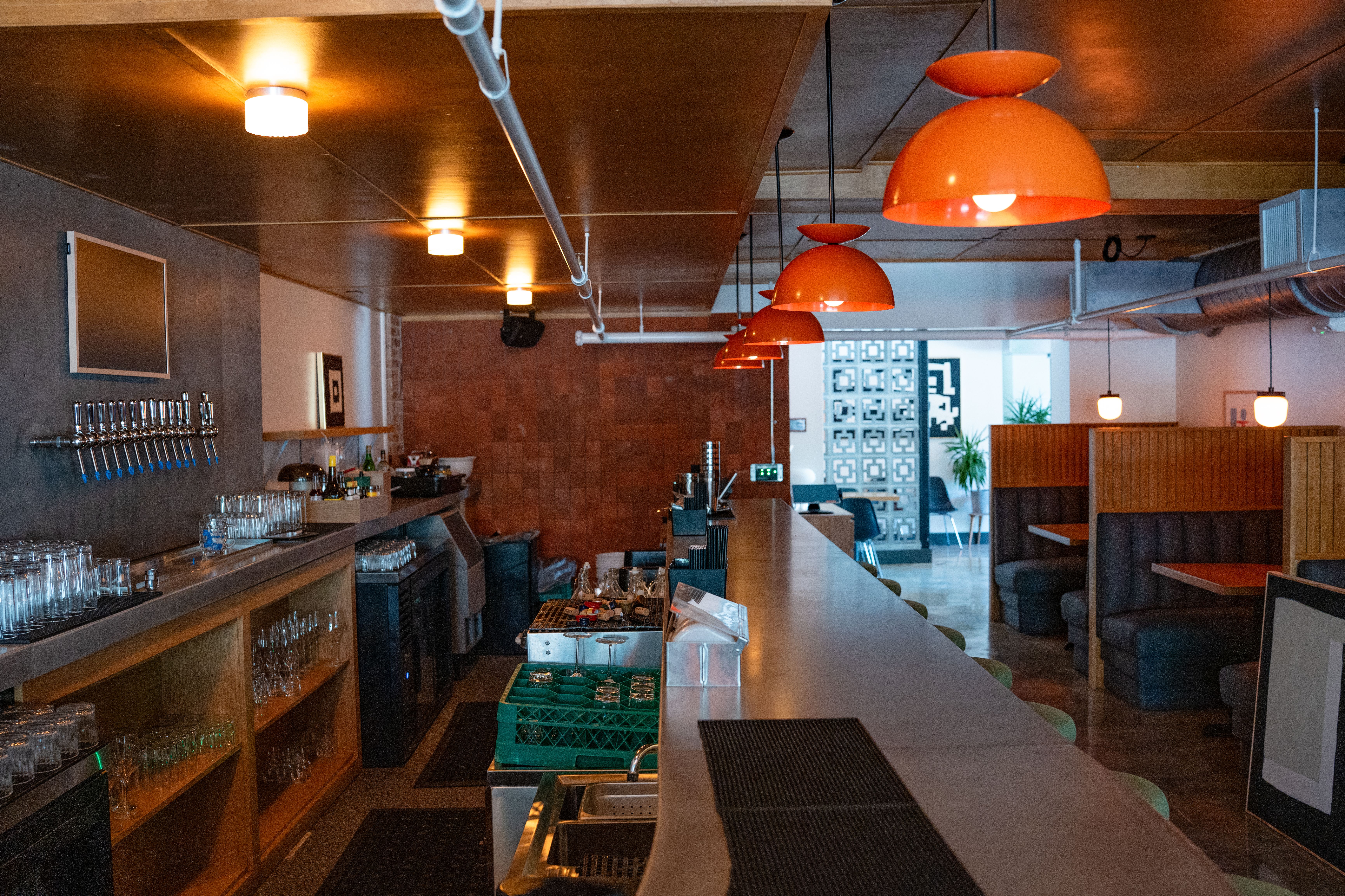 Stylish bar interior with orange pendant lights and empty booths creating a cozy atmosphere
