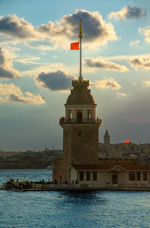 Free Maiden's Tower at sunset, Istanbul's skyline in the backdrop with vibrant clouds and tranquil water. Stock Photo