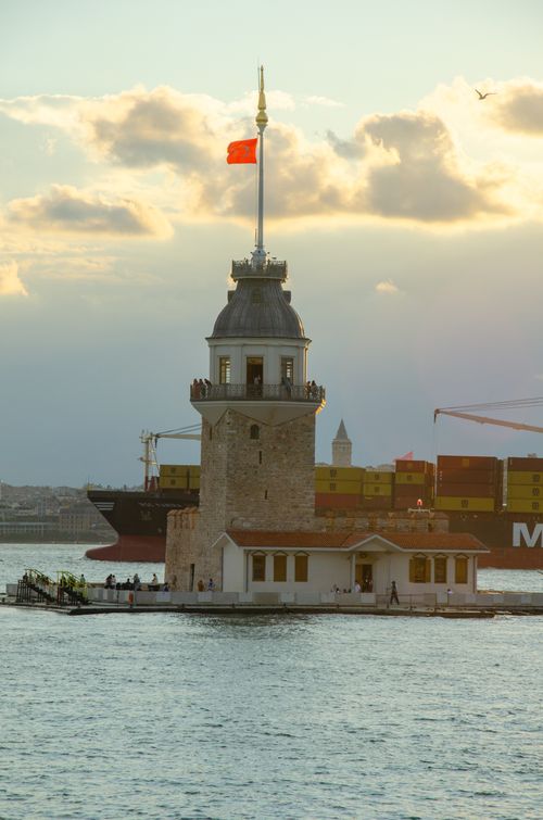 Free Serene view of Maiden's Tower in Istanbul at sunset with a cargo ship in the background. Stock Photo