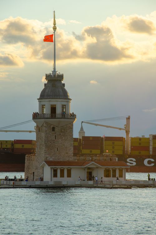 Free Captivating sunset view of the iconic Maiden's Tower on the Bosphorus Strait with a ship passing by in Istanbul, Turkey. Stock Photo