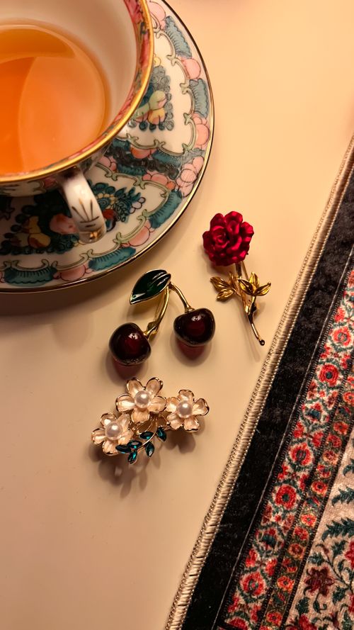 Free Tea cup with floral brooches and cherries on a stylish table setting. Stock Photo