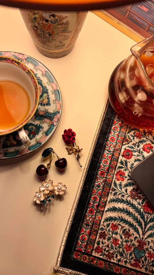 Free Charming tea setup with vintage porcelain, cherry earrings, and a colorful Oriental rug. Stock Photo