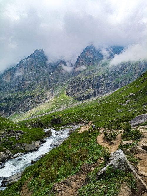Free Breathtaking view of lush green mountains and a winding river path, enveloped by clouds. Stock Photo